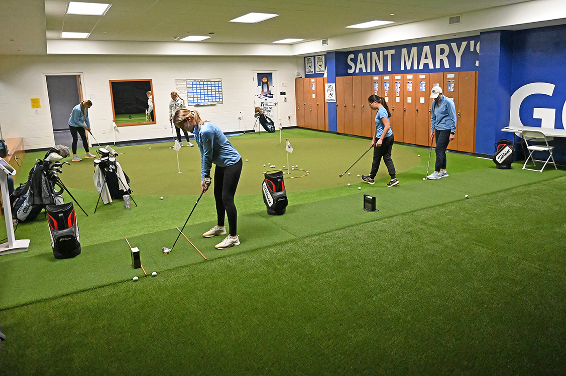 Five golfers utilize the various spaces of the golf room.