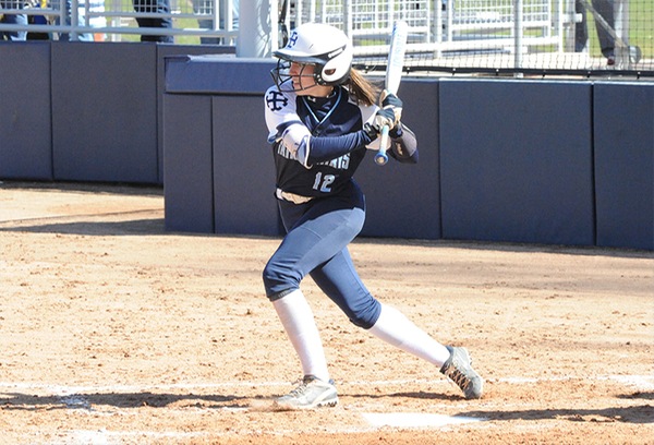 Kelsey Keilman, wearing a navy blue uniform with white socks and a white helmet, prepares to hit a pitch.