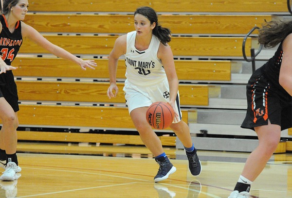 Giavanna Paradiso, wearing a white uniform, dribbles the ball with an opposing player visible to the left and to the right.