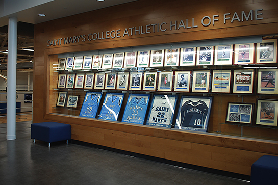 A wood, built-into-the-wall display case shows the Hall of Fame plaques as well as retired jerseys inside Angela Athletic & Wellness Complex.