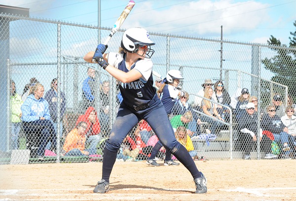 Megan Knudsen, wearing a blue uniform and white helmet, holds a bat and is ready to hit.