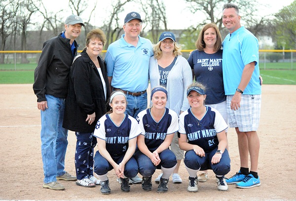 The three senior softball players, squatting in the front row, pose for a photo with their parents after the conclusion of the doubleheader.
