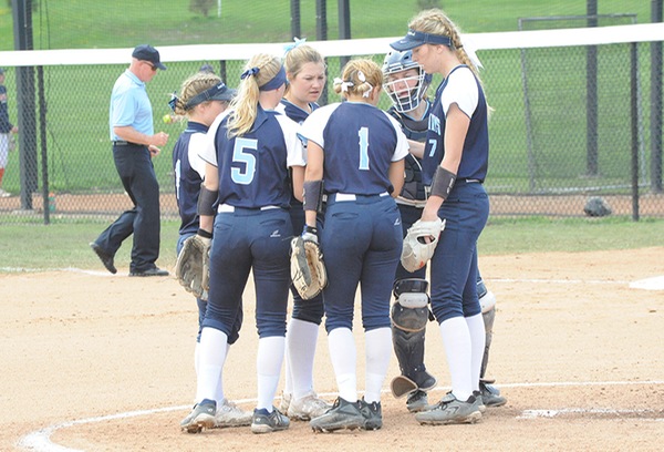 Several members of the Saint Mary's softball team huddle together at the start of an inning.