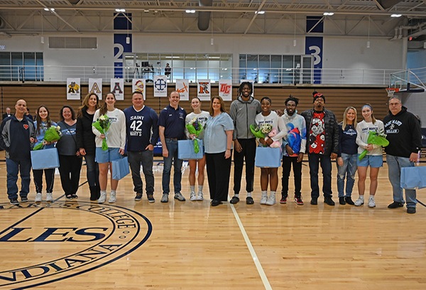 The senior members of the basketball team along with loved ones line up for a photo.