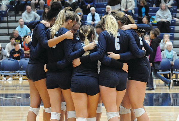 The team, wearing navy blue uniforms, huddles prior to the start of a match.